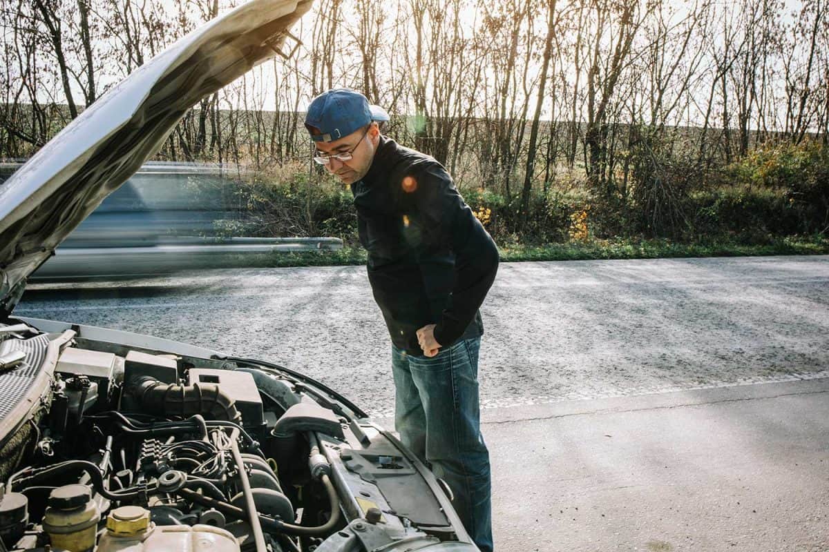 Young male looking at faulty car engine