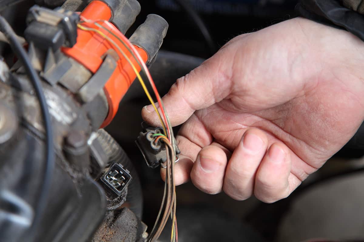 Mechanic's hand removes the connector from the coolant temperature sensor