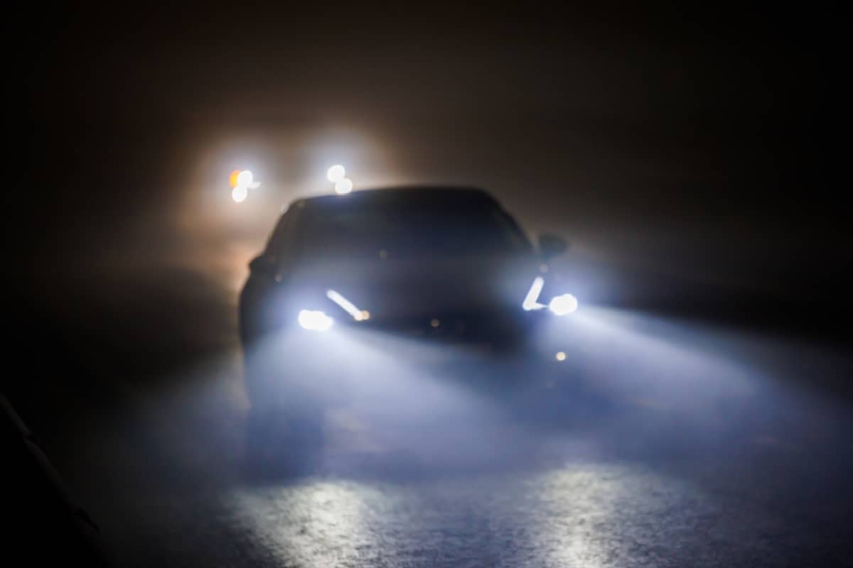 When is it legal to use a fog light - two blurred cars moving on empty night foggy road.