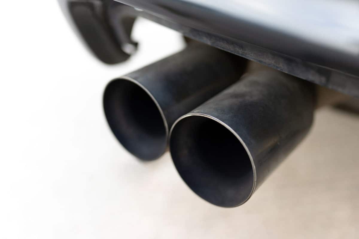 close up photo of a car exhaust tip, white car dual exhaust pipes