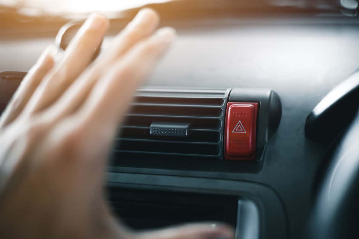 woman hand on front of the car aircon vents on a summer season