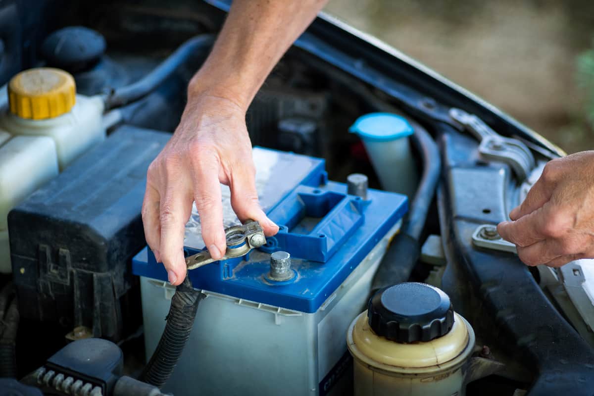 Man connecting the car battery to the vehicle with a wrench