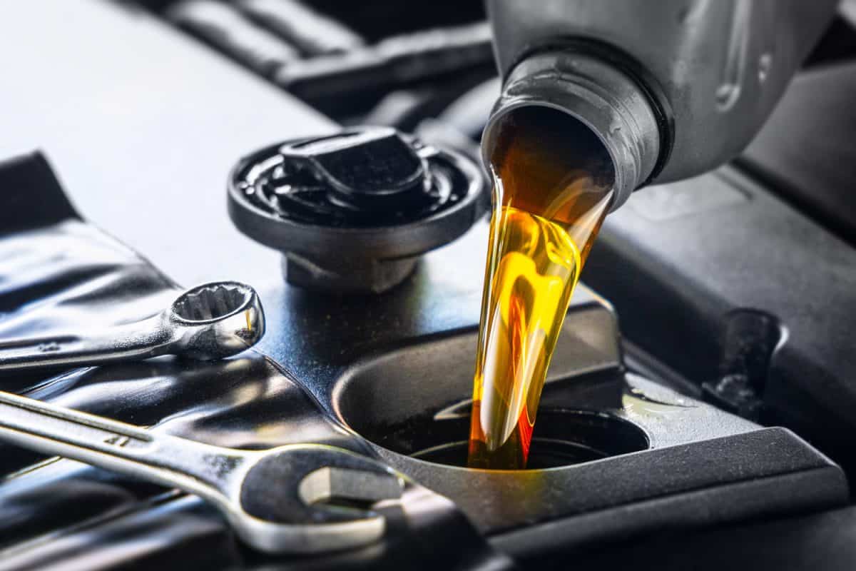 Pouring motor oil for motor vehicles from a gray bottle into the engine, , oil change, auto repair shop, service,

