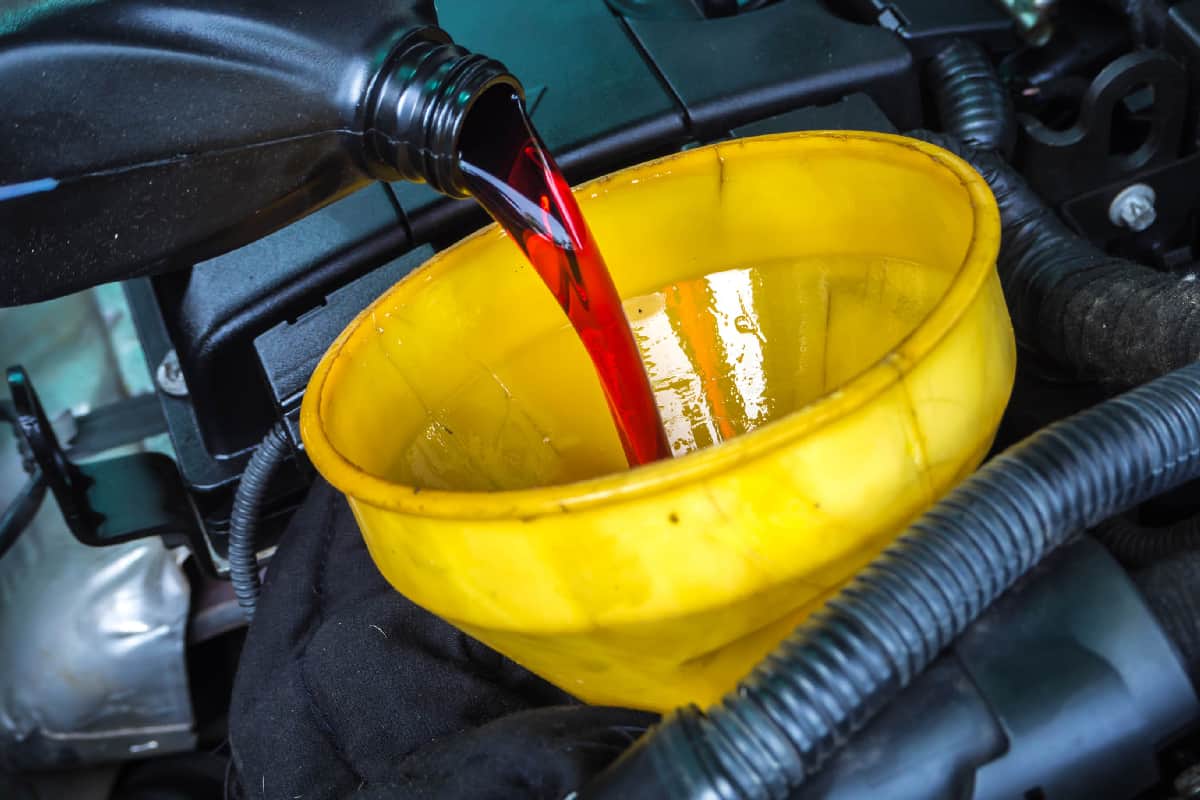 Transmission oil fill up in a car engine with yellow cone spire shape container