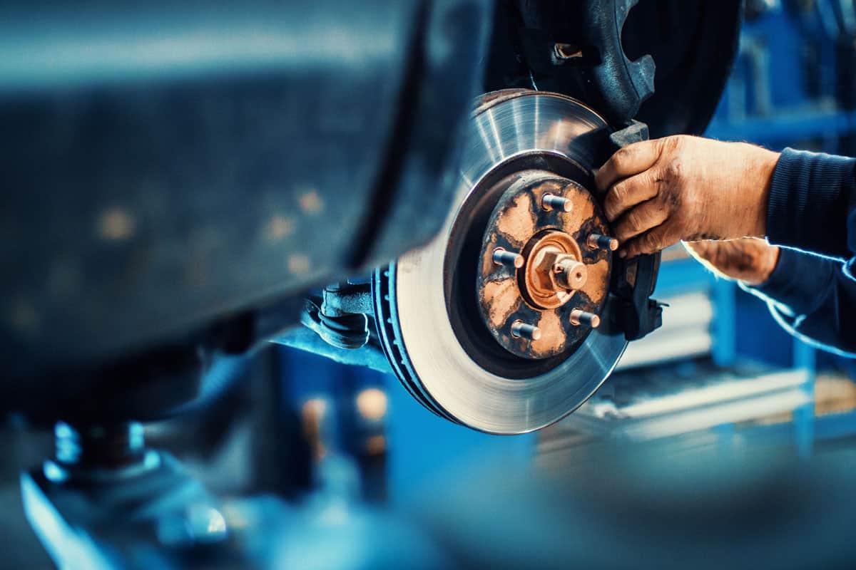 photo of a Car service procedure man mechanic repairing car brake rotor disc