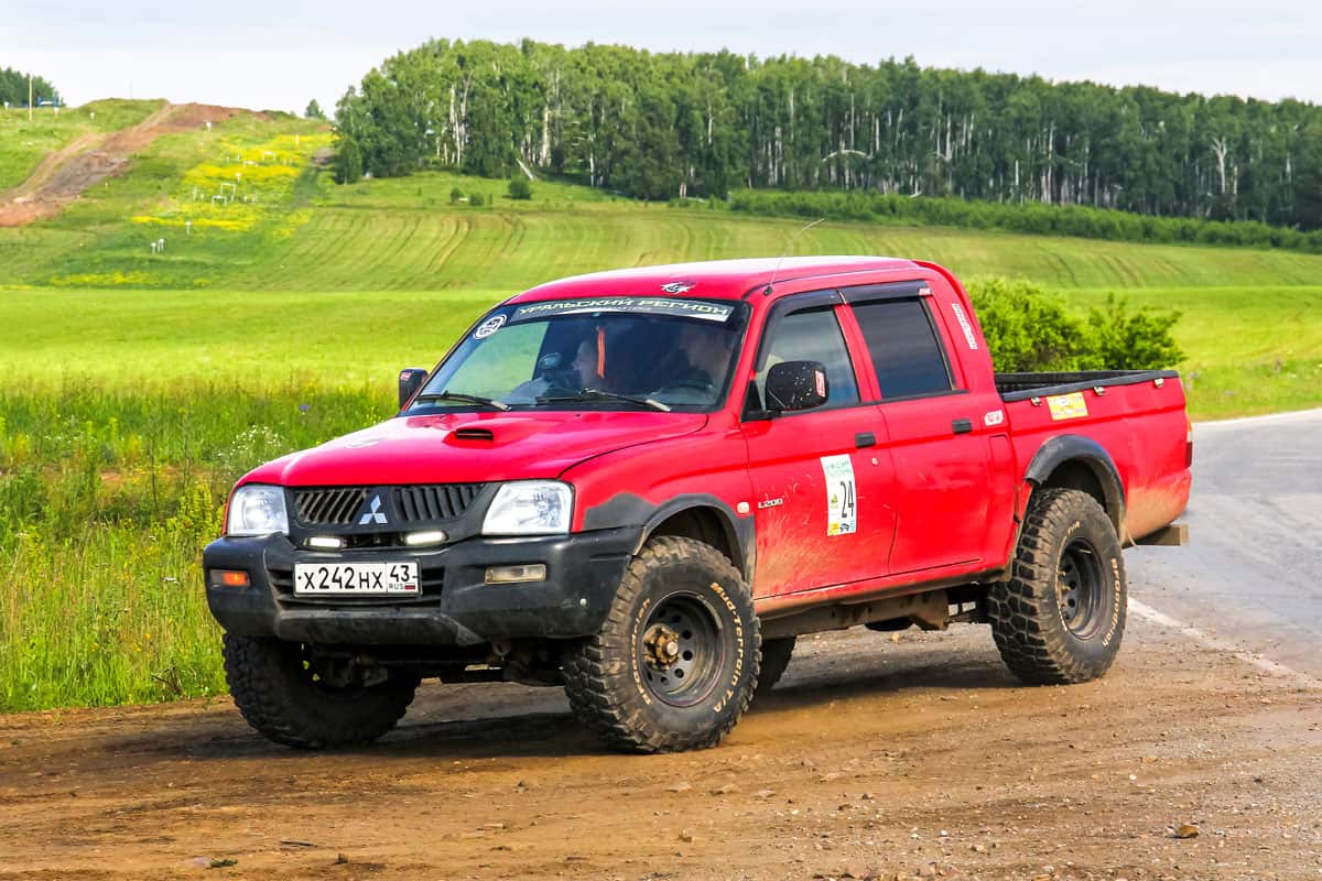 bright red colored mitsubishi l200 old version with mud tires and off road mags ready for off roading