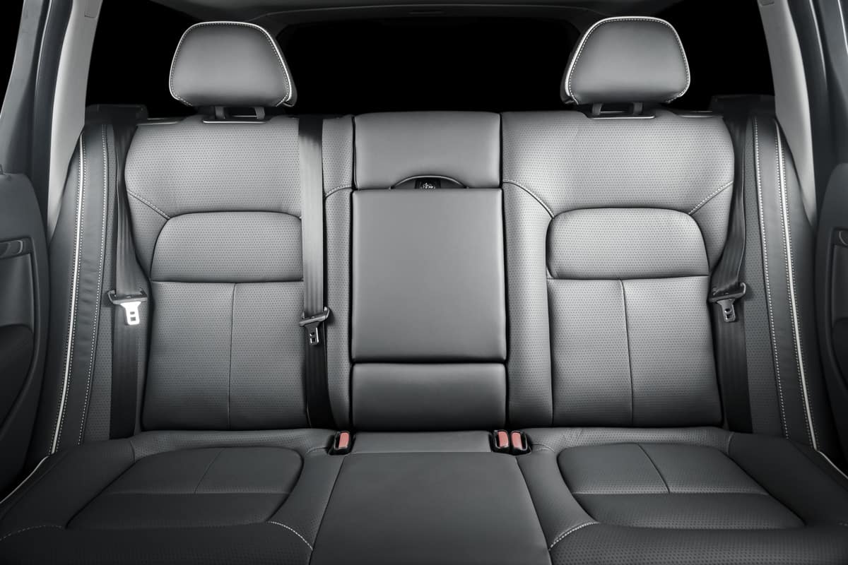 Back passenger seats in modern luxury car, frontal view, black perforated leather.