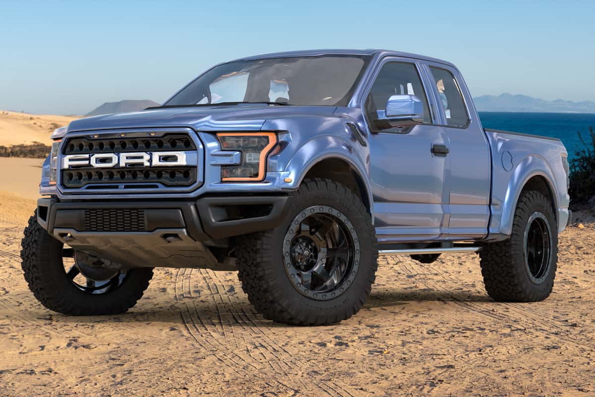 Ford F-150 Raptor - Most Extreme Production Truck On The Planet standing on a sand dune by the ocean.