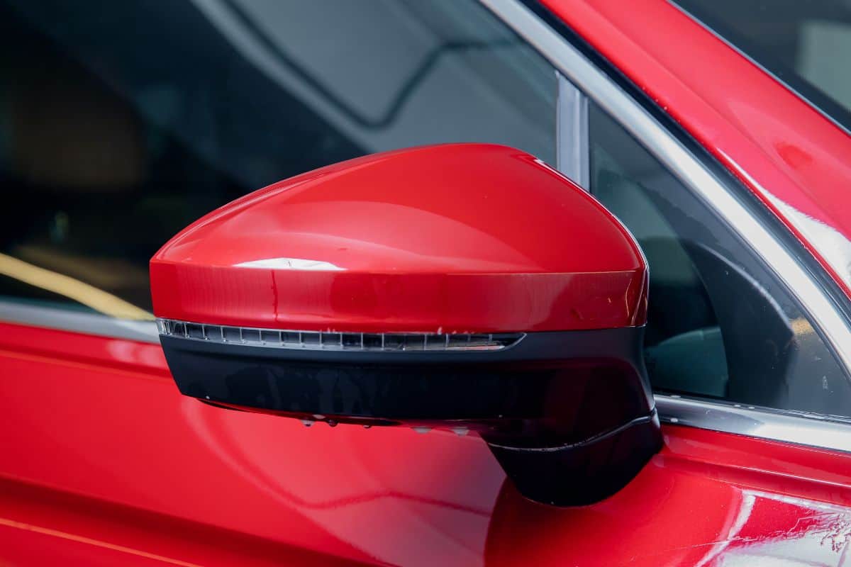 Installs-vinyl-film-for-protect-paint-body-side-mirrors-red-car.