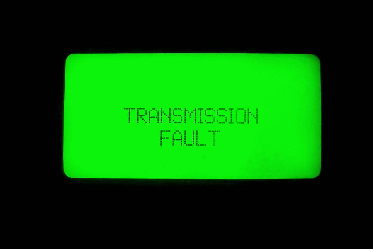 Old retro display panel with green glowing light, showing transmission fault. Car transmission error alert for faulty gear box system.
