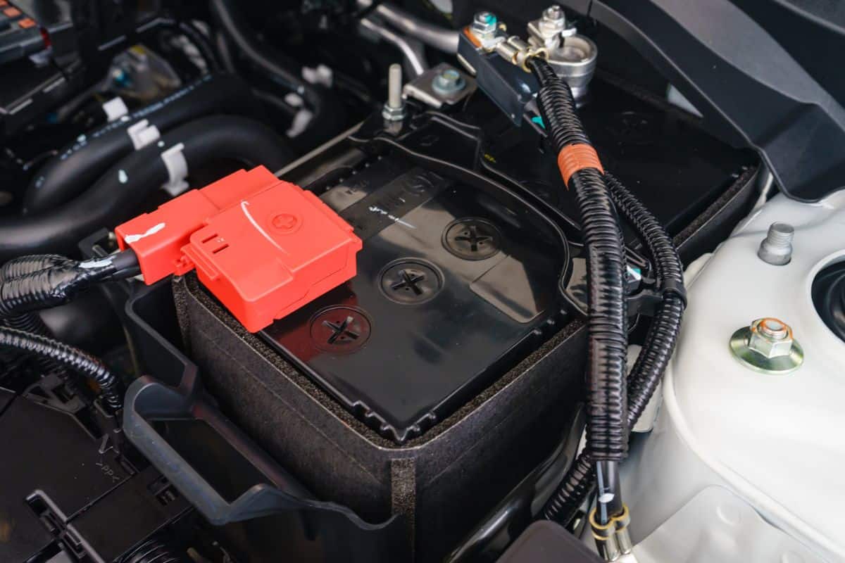 close-up on new small eco car battery installed in the compartment showing good arrangement and safety, clear communicated design of electrical connector and warning pictogram signs on the top cover
