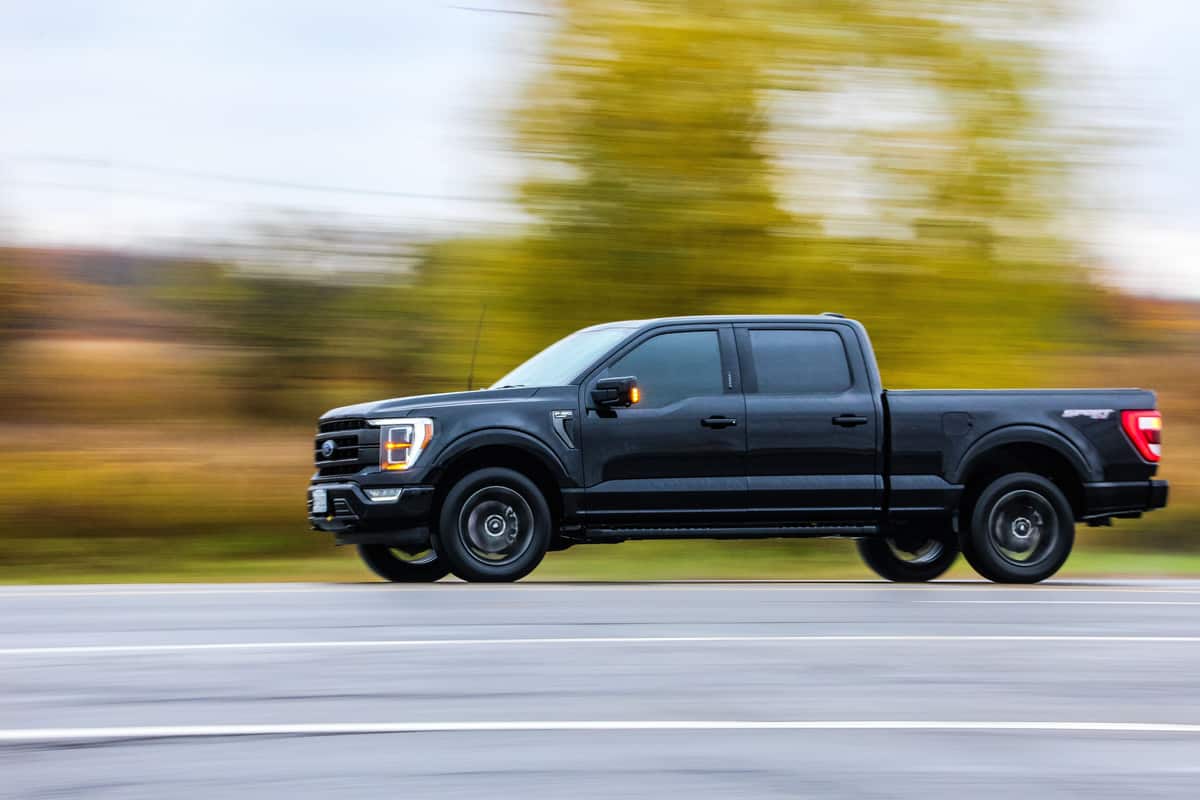 A black colored Ford F150 moving fast on the highway