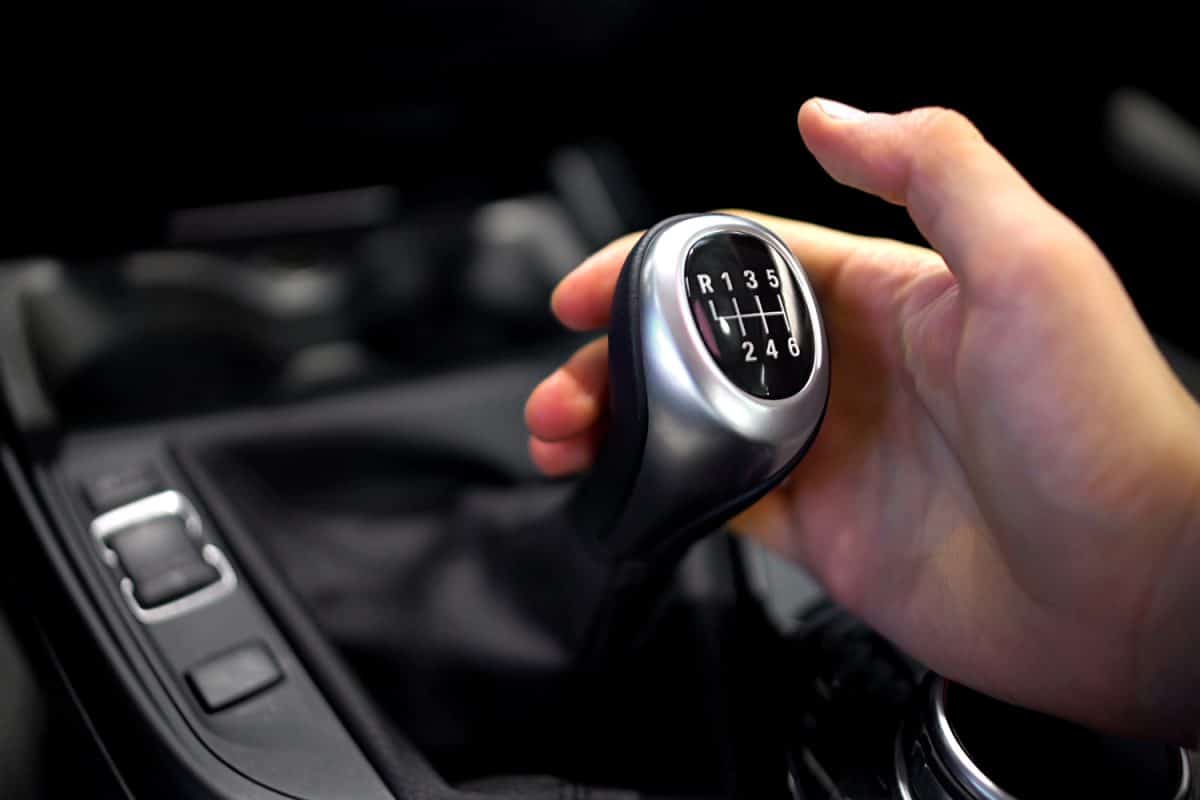 Male hand holding manual gearbox in car, test drive of new automobile, closeup
